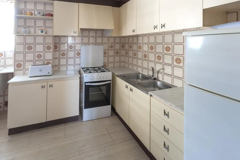 Una cocina con gabinetes blancos, una estufa y un fregadero doble.