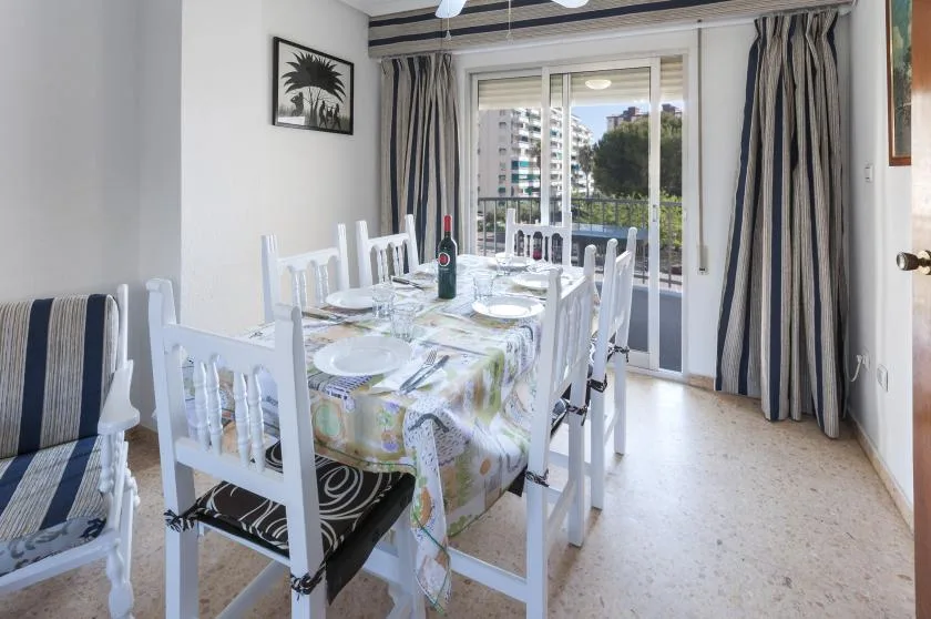 Un comedor con la mesa puesta junto a puertas de vidrio que dan a un balcón.