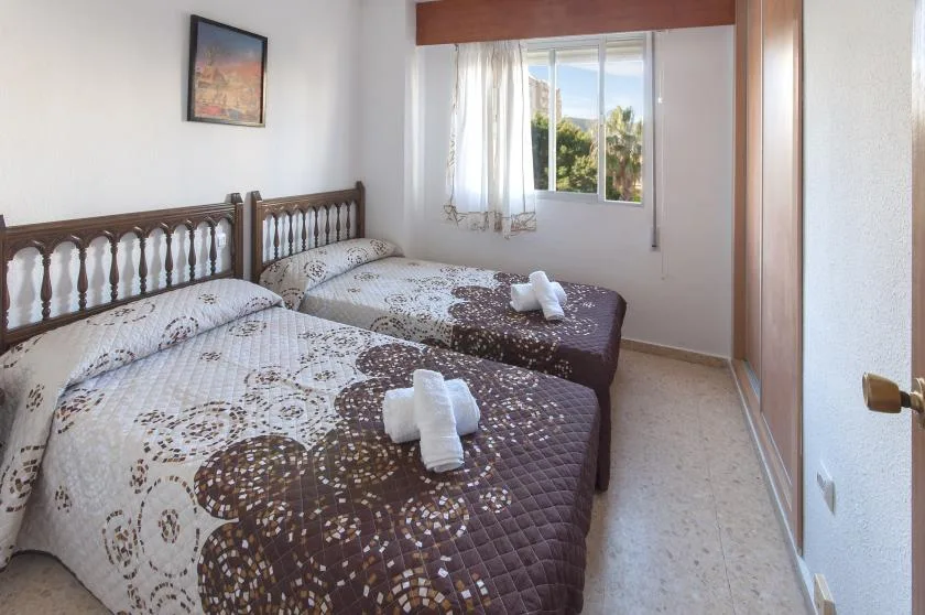 Un dormitorio con dos camas vestidas con ropa de cama estampada junto a una ventana.