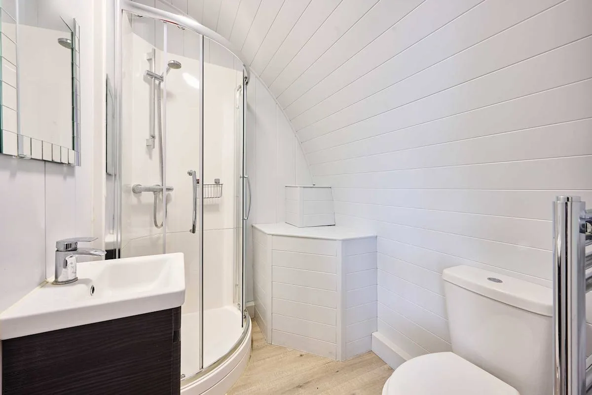 A bright bathroom with a glass shower, sink, and toilet.