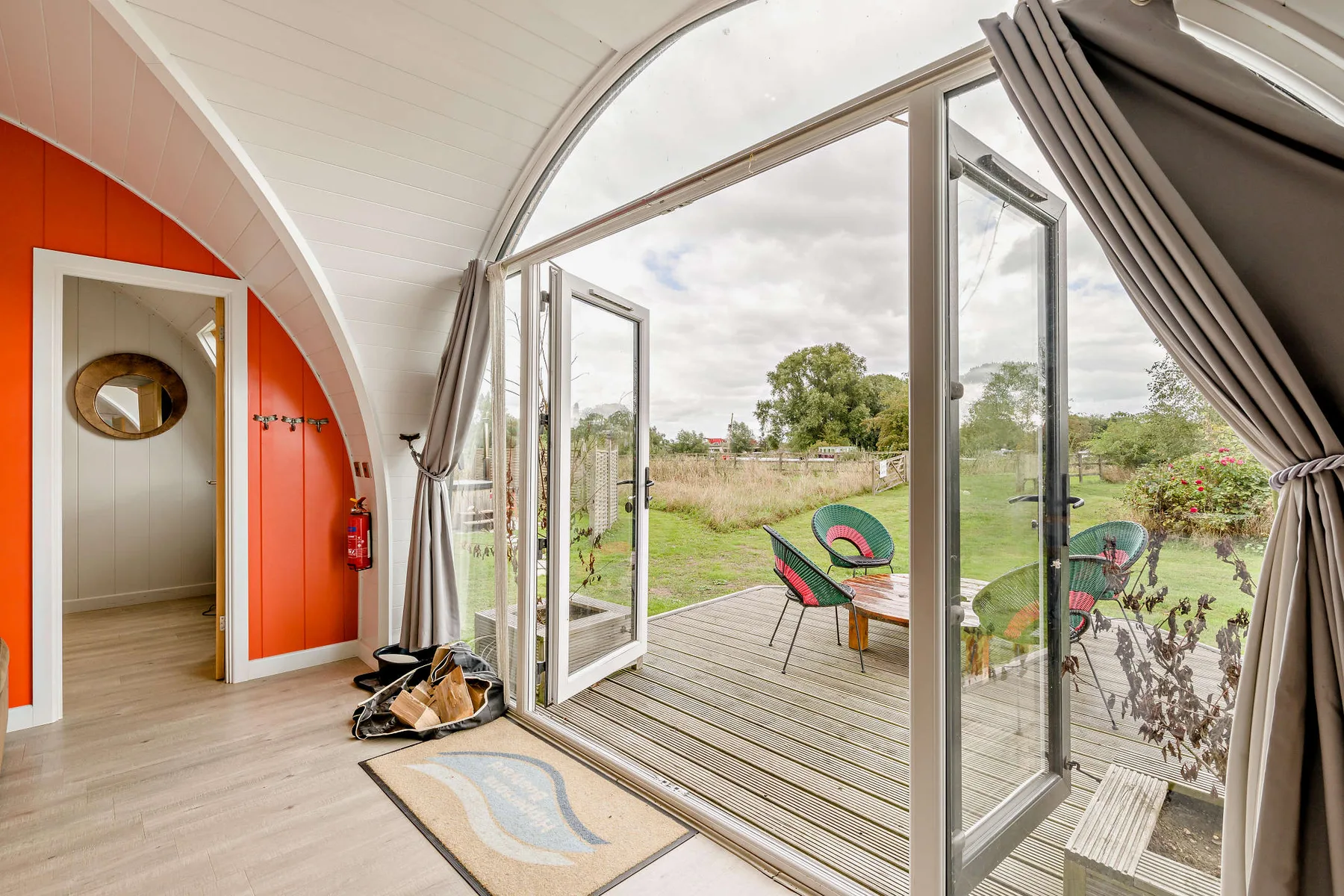 A bright room opens onto a wooden deck through large glass doors.