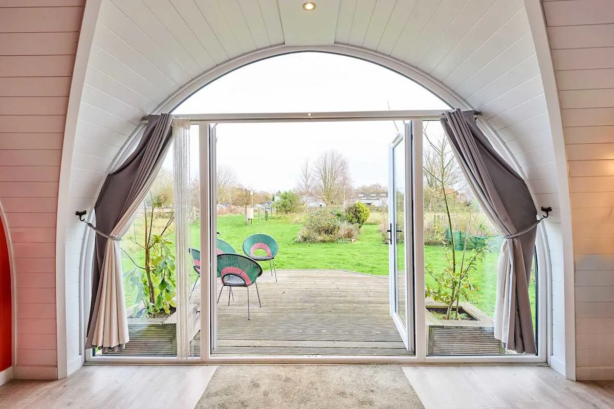 An arched sunroom opens onto a garden patio with outdoor seating.