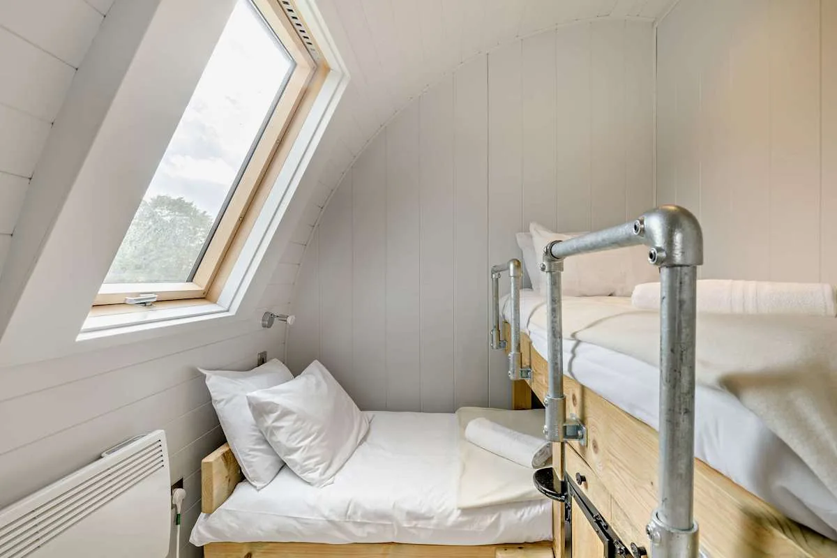 A compact bedroom with a sloped ceiling, a skylight, and beds.