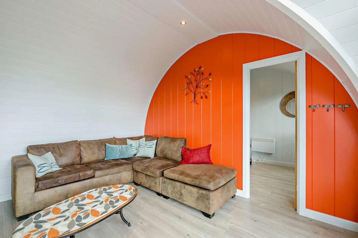 A living room with a sectional seating area beside an orange arched wall.