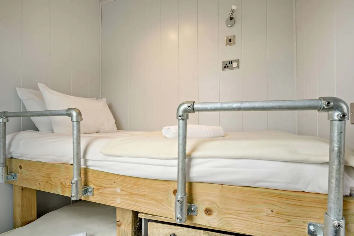 A bedroom with white bedding and a metal safety rail beside the bed.