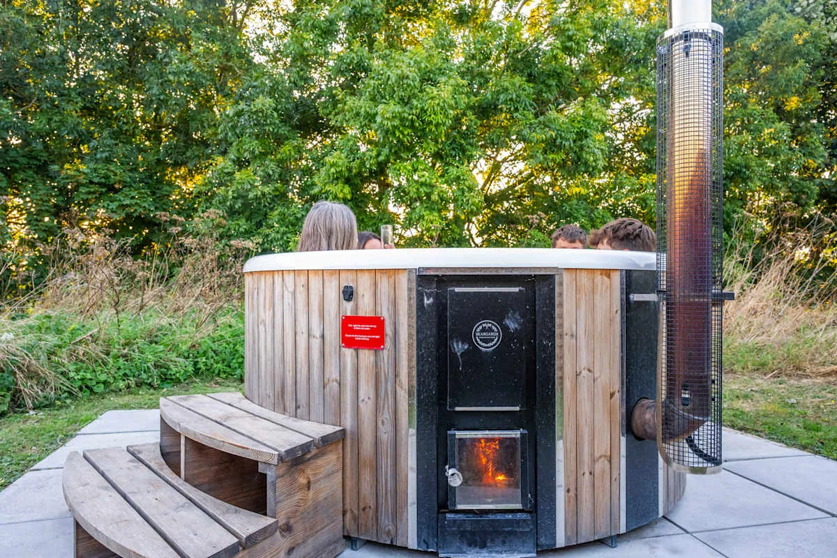 A round outdoor hot tub sits on a paved patio surrounded by trees.