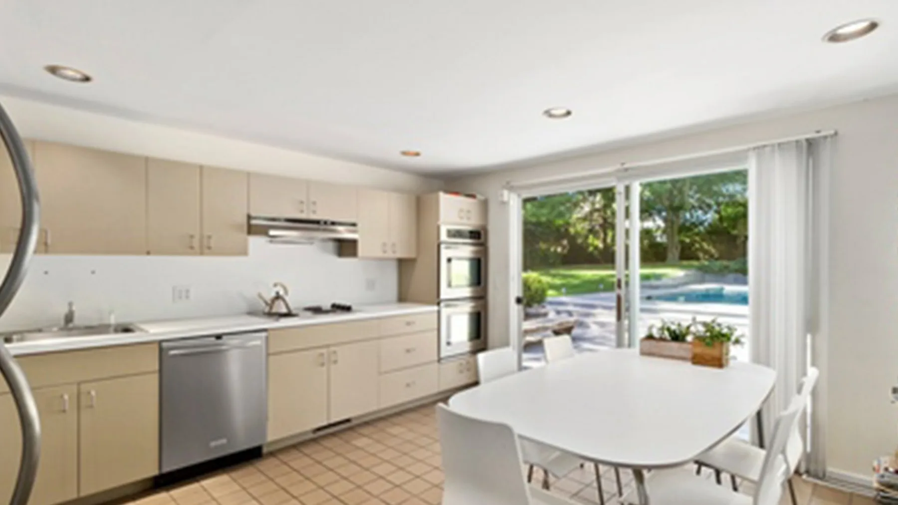 Una cocina luminosa con comedor se abre a un patio con piscina.