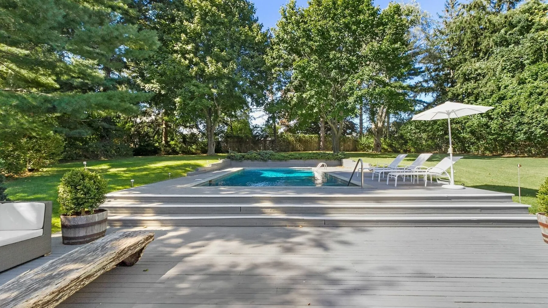 Una piscina al aire libre junto a una amplia terraza con asientos de patio.