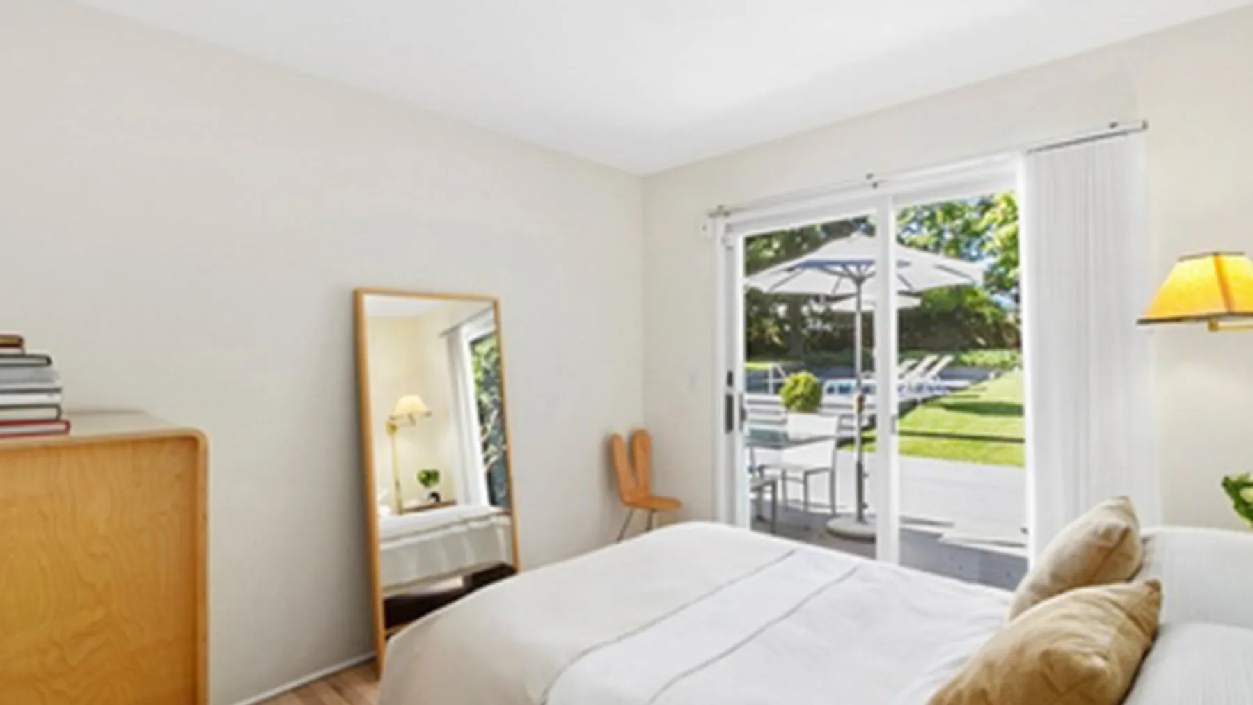Un dormitorio luminoso con una cama junto a puertas corredizas de vidrio que dan a un patio.