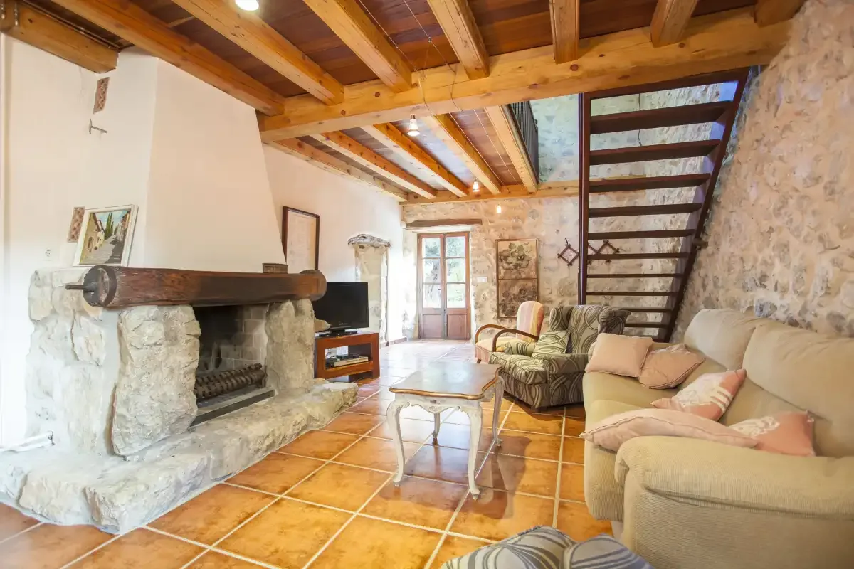 A living room with a stone fireplace, seating, and a staircase.