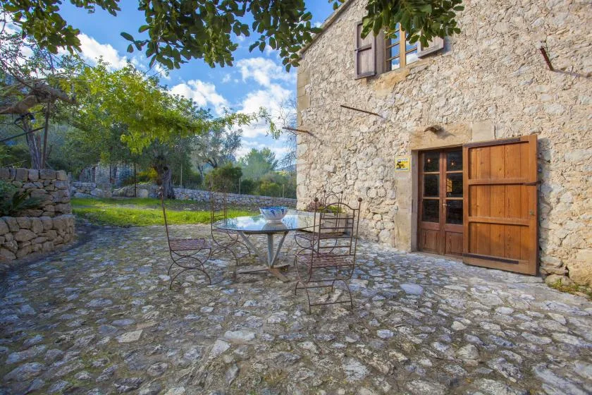 A stone courtyard beside a rustic stone building, with outdoor seating.