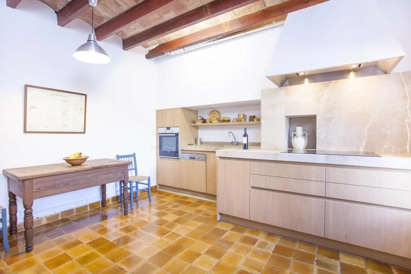 A bright kitchen with a wooden dining table and exposed ceiling beams.