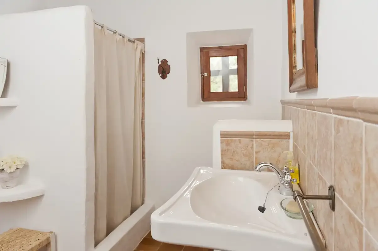 Bathroom with a white sink, tiled walls, and a curtained shower area.