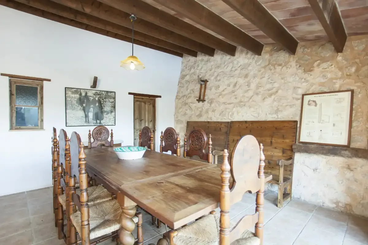 A rustic dining room with a long wooden table and carved seating.