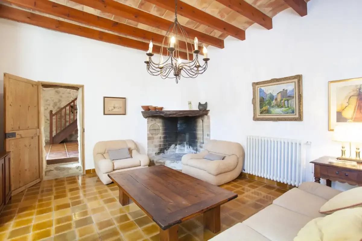 A living room with seating around a fireplace and a wooden coffee table.