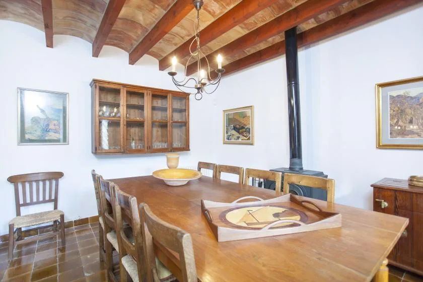 A dining room with a long wooden table beneath exposed ceiling beams.