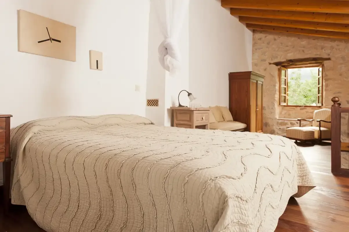 A bedroom with a large bed, bedside table, and window.