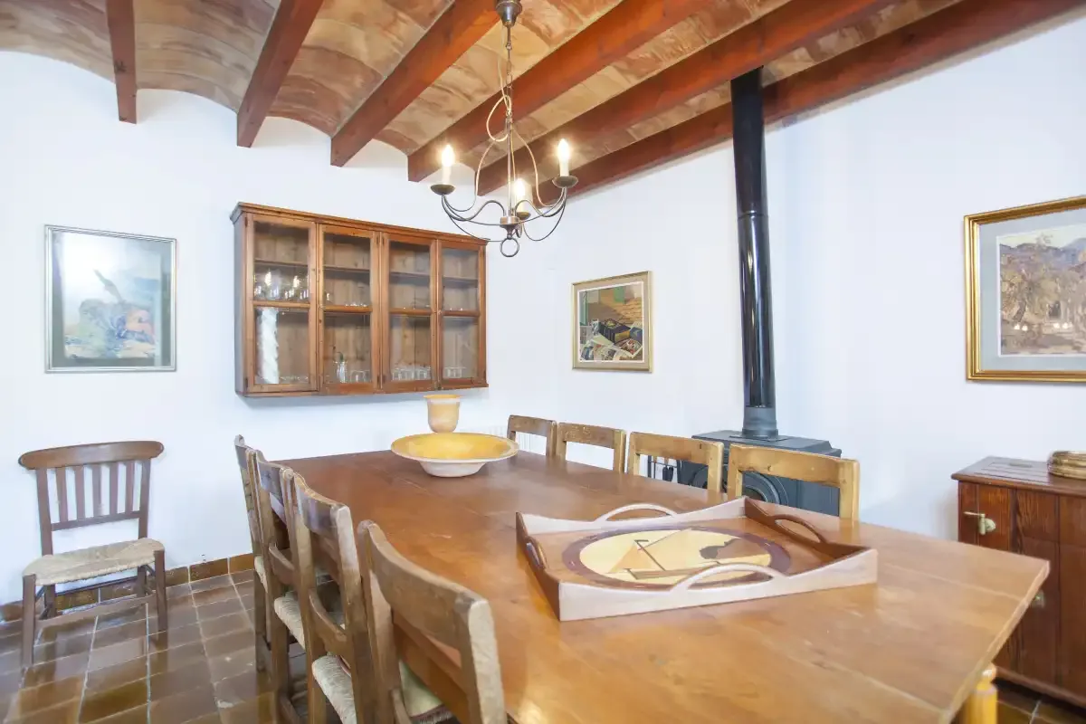 A dining room with a long wooden table beneath exposed ceiling beams.