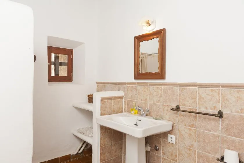A tiled bathroom with a pedestal sink, wall mirror, and towel rail.