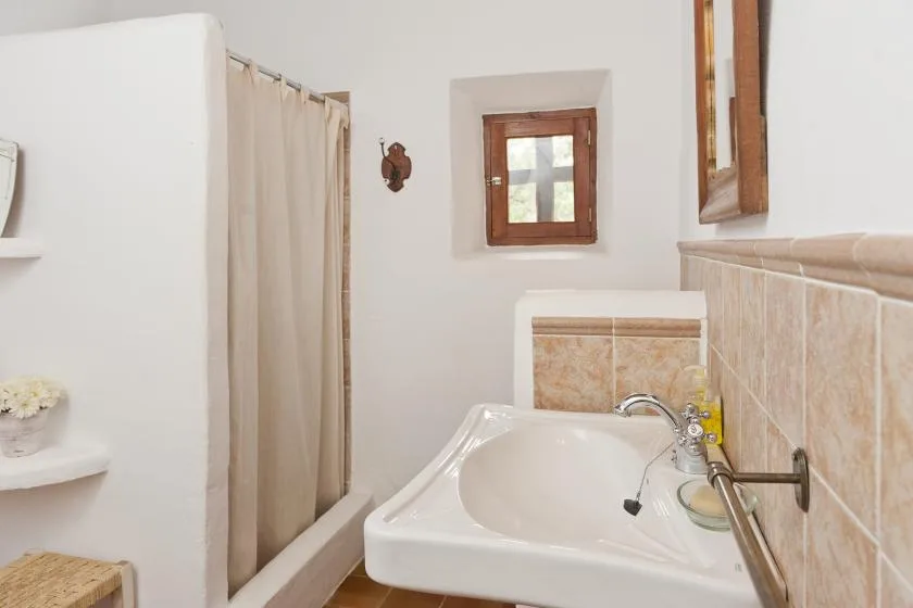 A bathroom with a bathtub, tiled walls, and a small window.