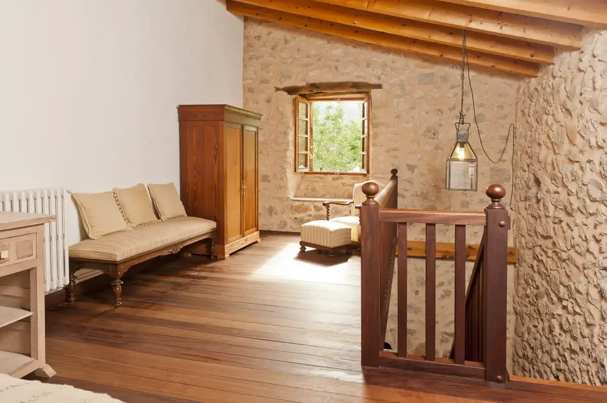 A rustic interior room with wooden seating, a wardrobe, and a window.