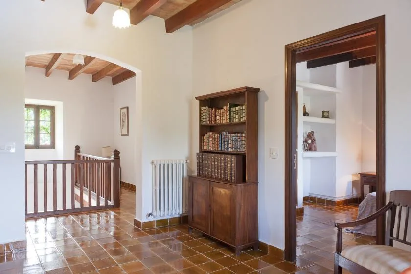 A bright interior room with a wooden bookcase and an arched opening.