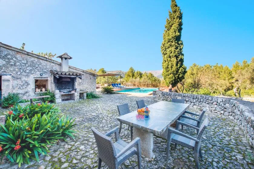 A stone patio with an outdoor dining table overlooks a swimming pool.