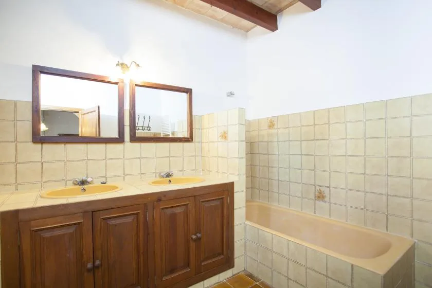 A bathroom with a wooden vanity, twin sinks, and a bathtub.