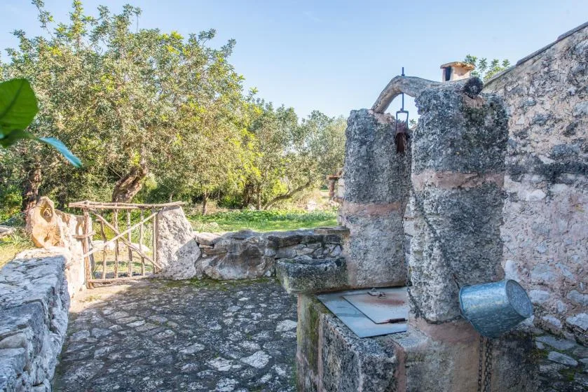 A stone courtyard with a rustic gate and a built-in water fountain.