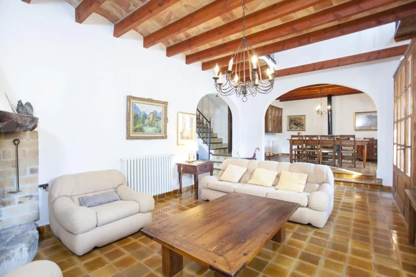 A bright living room with seating around a wooden coffee table beneath exposed beams.