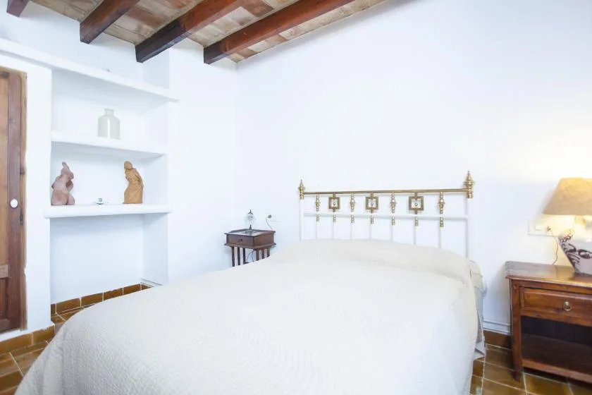 A bedroom with a bed, built-in shelves, and exposed wooden ceiling beams.