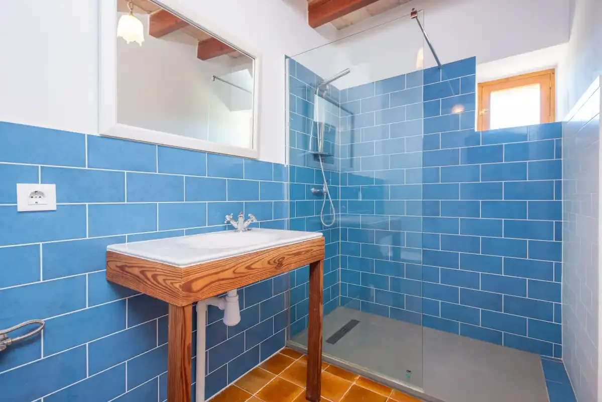 A bathroom with a wooden vanity and blue tiled walls.