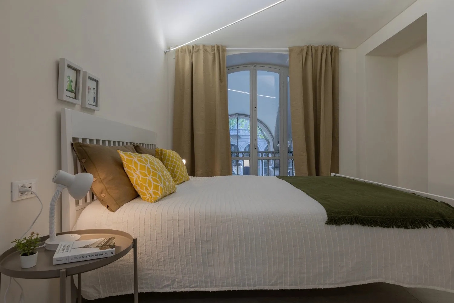 A bedroom with a neatly made bed and curtained window.