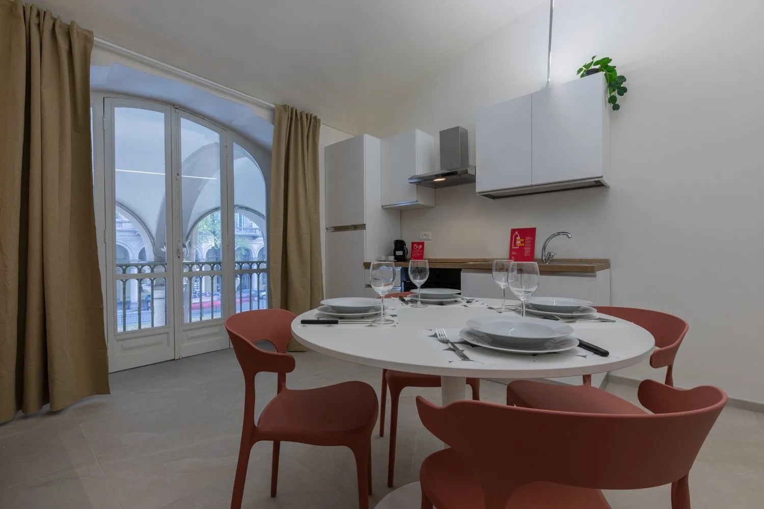 Comedor con una mesa puesta y grandes puertas de vidrio arqueadas.