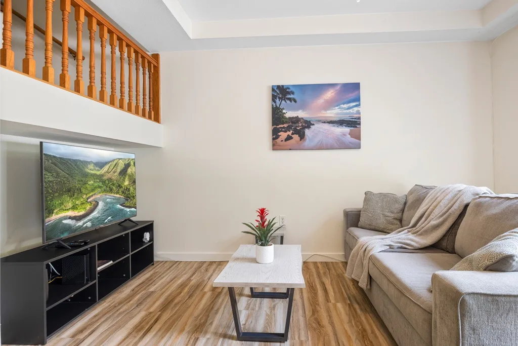 Una sala de estar con asientos, un televisor y una pequeña mesa de centro.