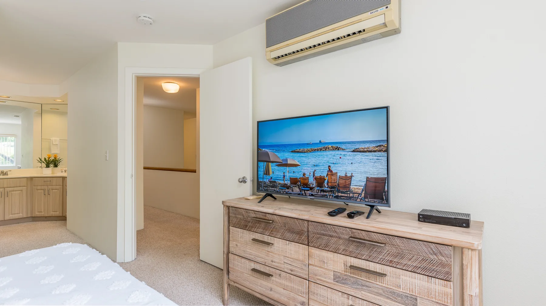 Un dormitorio con un televisor sobre una cómoda y una puerta abierta.