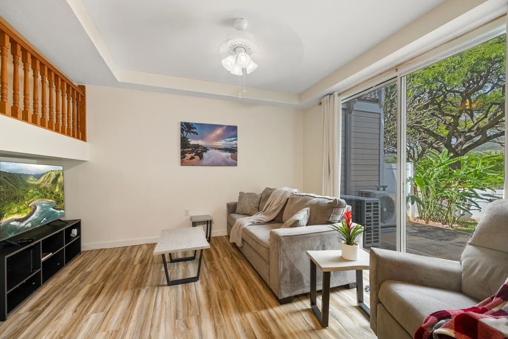 Una sala de estar con asientos, una mesa de centro y puertas corredizas de vidrio hacia la vegetación.