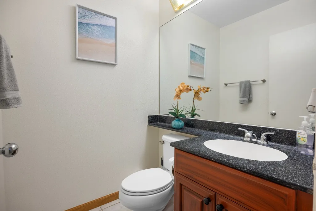 Un baño con tocador, lavabo, inodoro y una imagen de playa.
