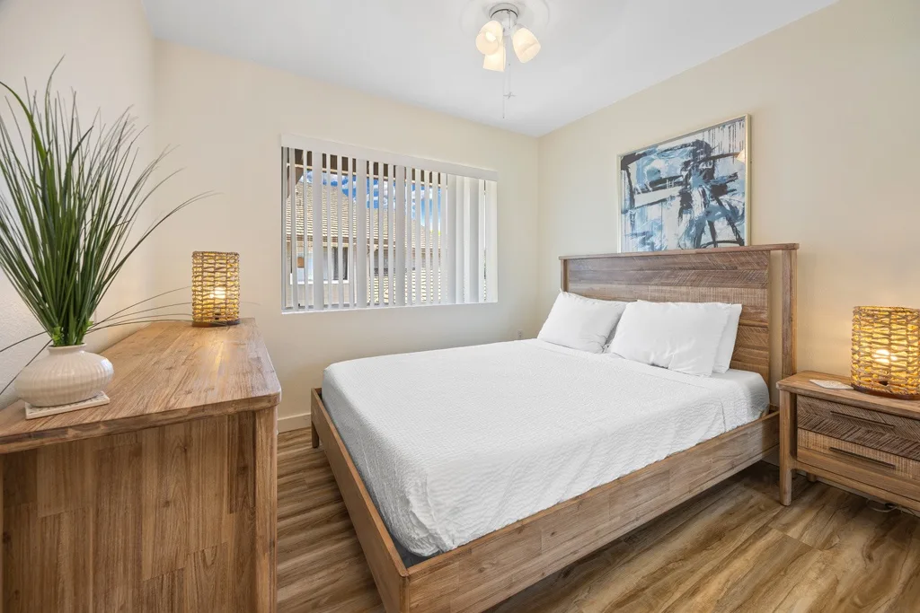Un dormitorio con una cama de madera, ropa de cama blanca y muebles a juego.