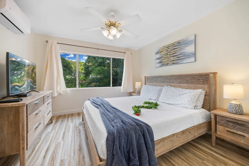 Un dormitorio con una cama de madera, una mesita de noche y una ventana amplia con vistas a la vegetación.