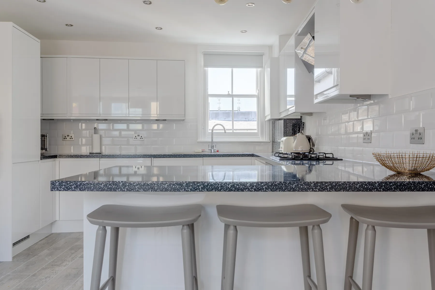 A bright kitchen with white cabinets and a breakfast counter.