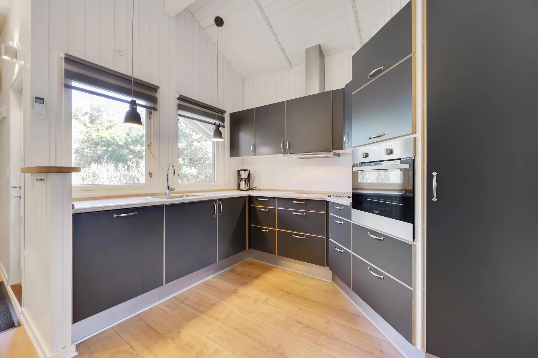 A bright kitchen with dark cabinets, a countertop, and built-in appliances.
