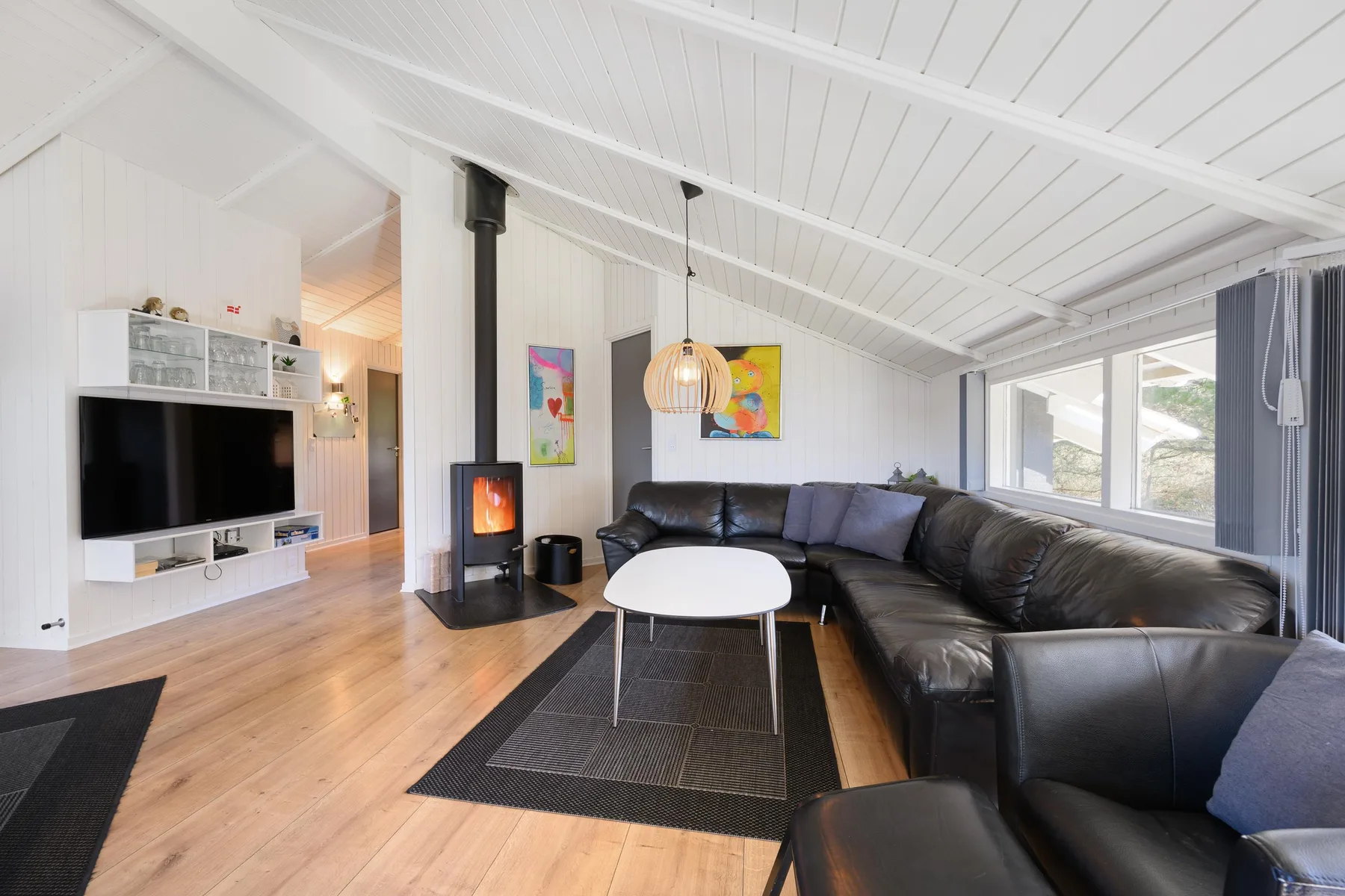A living room with dark seating, a coffee table, and a wall-mounted television.