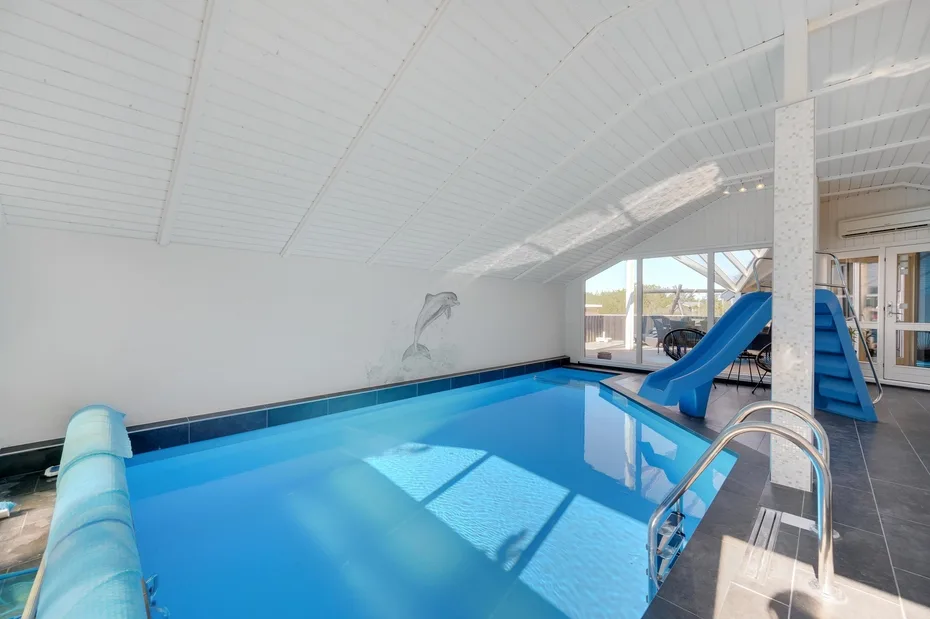 An indoor swimming pool with a blue slide beside the water.