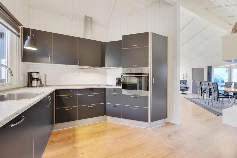 A modern kitchen with dark cabinets, light countertops, and wood flooring.