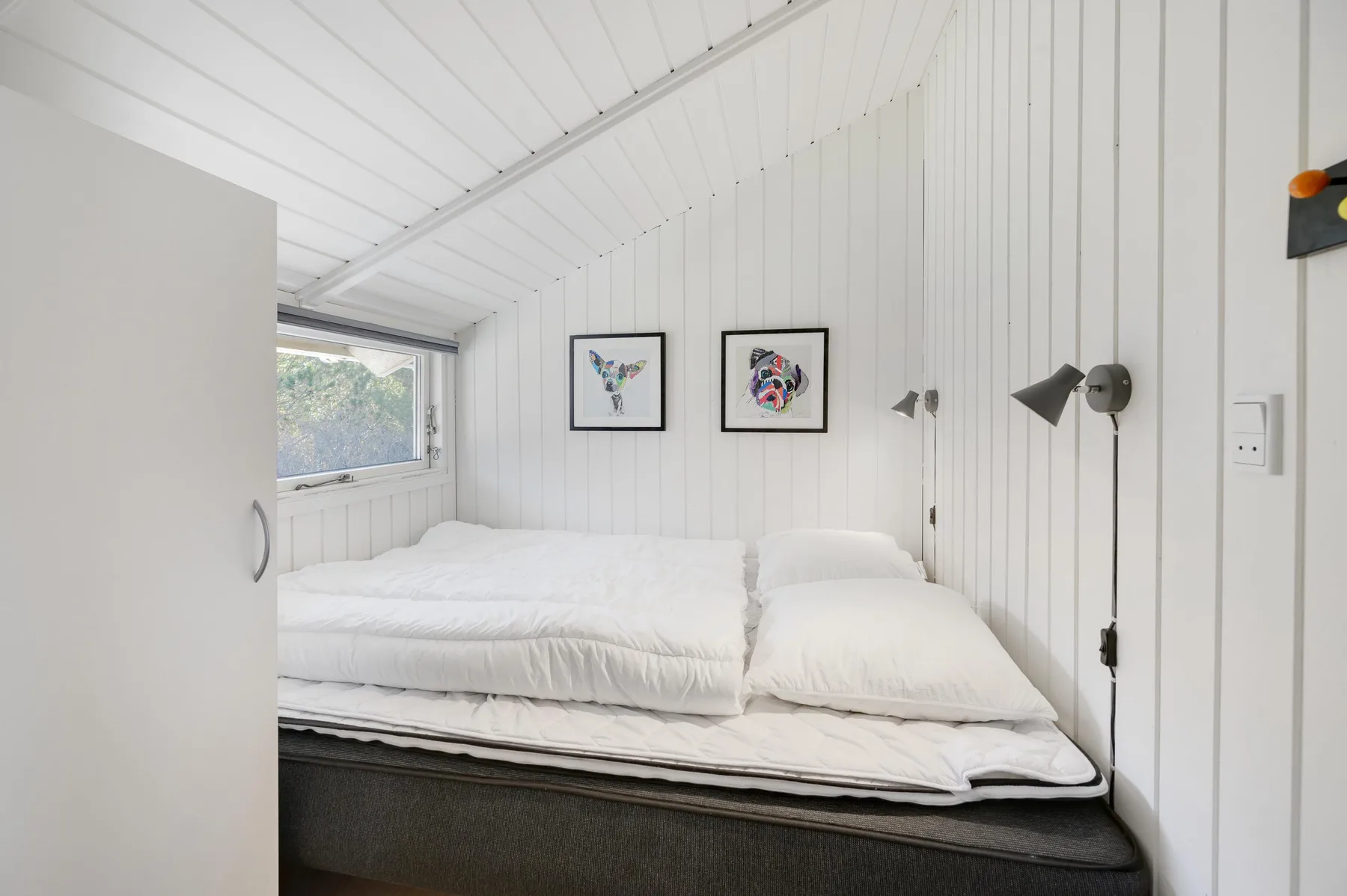 A bedroom with a bed, wall art, and a window.