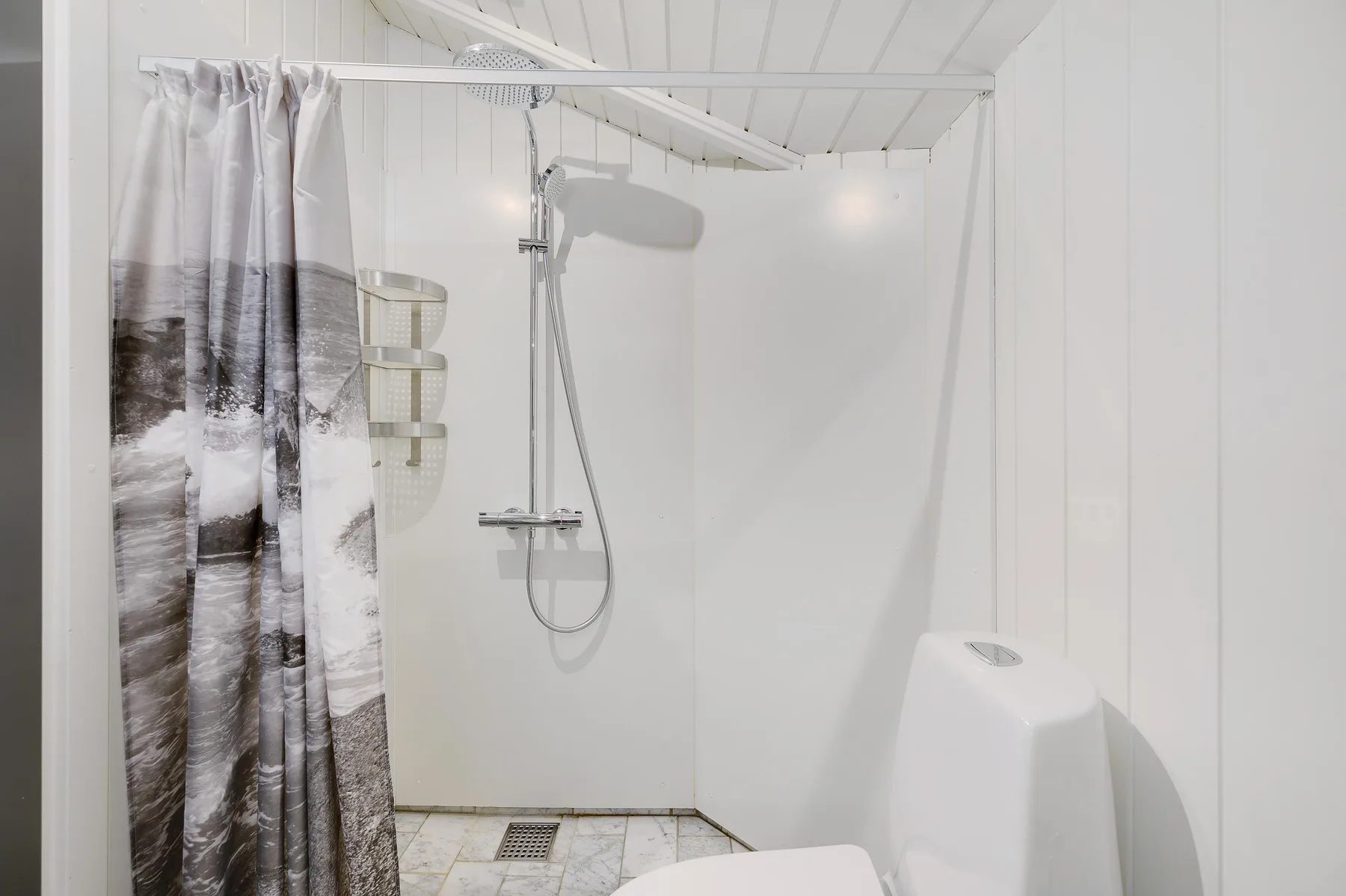 A bright bathroom with a shower and patterned curtain.