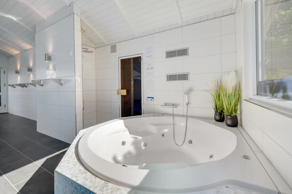 A spacious bathroom features a large round soaking tub and potted plants.