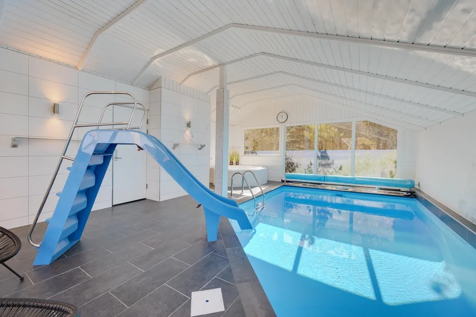 An indoor swimming pool with a blue slide beside the water.
