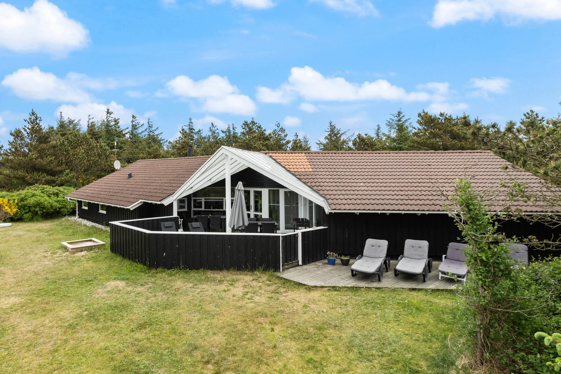 A single-story vacation house with a glass-fronted patio and outdoor seating.